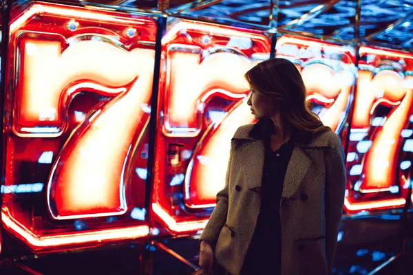 একজন নারী তার ল্যাপটপে অনলাইন গেম খেলছেন, চারপাশে নীলন আলোয় ক্যাসিনো উপাদান — যা KK33E–এর বৈচিত্র্যময় গেম সংগ্রহকে প্রদর্শন করে।